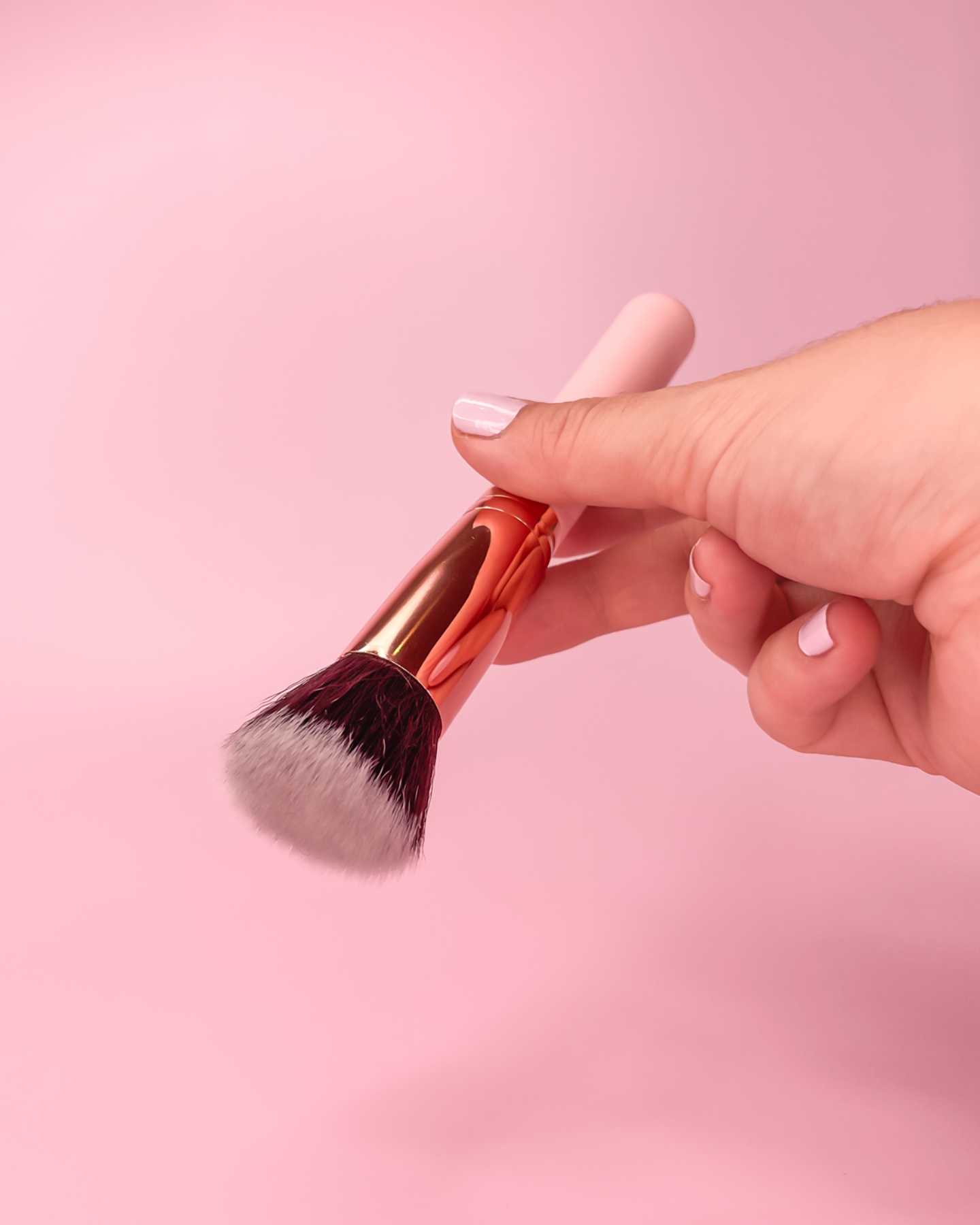 hand holding a pink fluffy brush